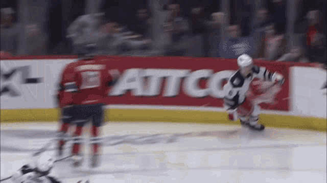 a hockey game is being played in front of a banner that says " attco "