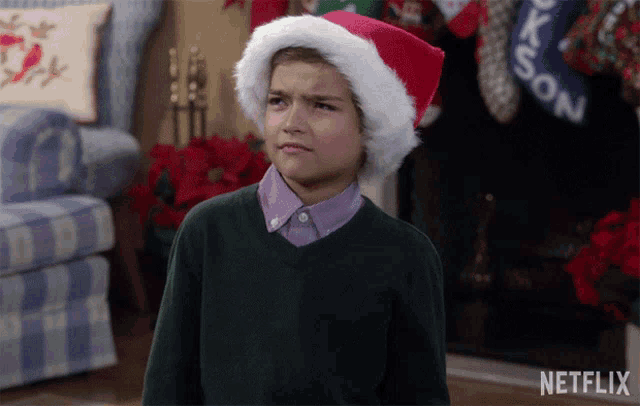 a boy wearing a santa hat is standing in front of a fireplace with stockings that say jackson on them