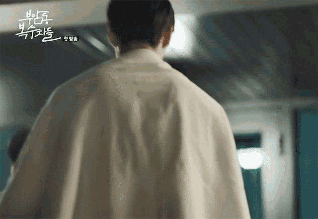 a man in a white robe is walking down a hallway with chinese writing on the ceiling