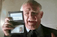 a man in a suit and tie is holding a wallet with two id cards on it .