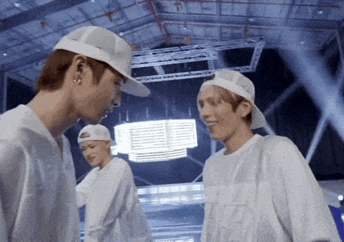 a man wearing a white baseball cap talks to another man