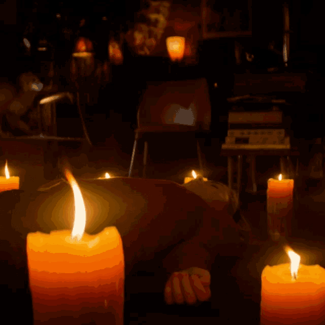 a person is laying on the floor with candles around them