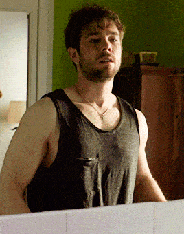 a man in a tank top looks at himself in the mirror