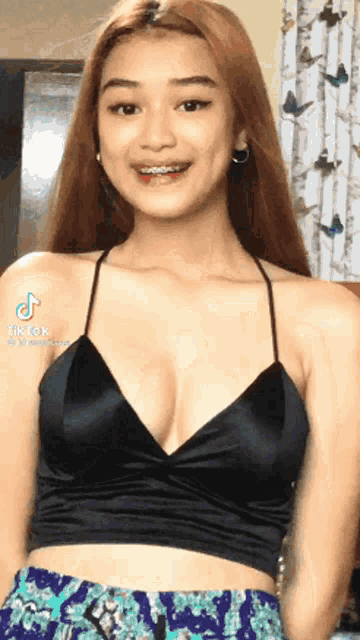 a woman with braces on her teeth is wearing a black halter top and blue shorts .