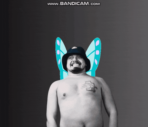 a shirtless man with a tattoo on his chest is wearing fairy wings and a hat