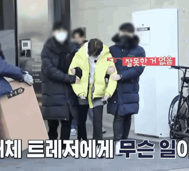 a person in a yellow jacket is being helped by a group of people in black coats