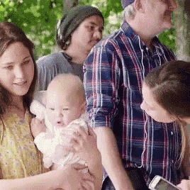 a woman is holding a baby in her arms while a man looks at his phone