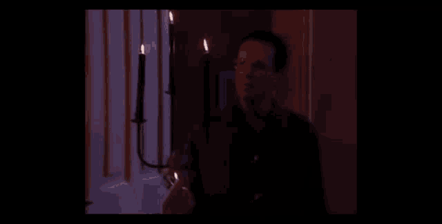 a man is holding a candle in front of a door