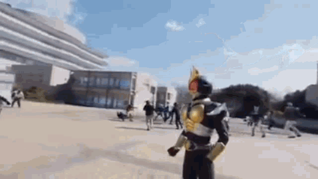 a man in a superhero costume is standing in front of a group of people in a park .