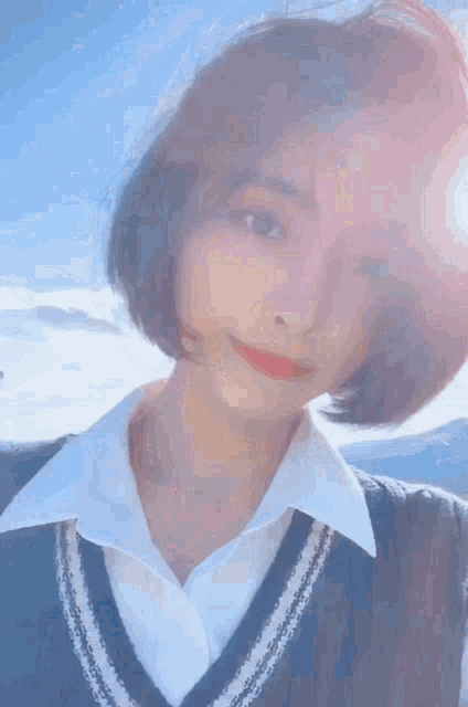 a woman with short hair wearing a white shirt and a blue vest