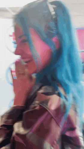 a woman with blue hair is laughing and covering her mouth with her hand