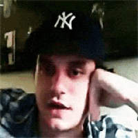 a man wearing a new york yankees hat is laying down with his hand on his face .