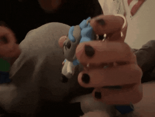 a person with black nails is holding a stuffed animal in their hands