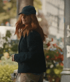 a woman wearing a hat and a jacket is walking down a street