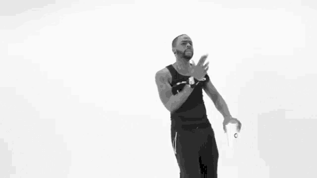 a man in a black tank top is dancing in a black and white photo .