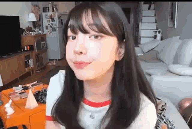 a young woman is sitting on a couch in a living room making a face .