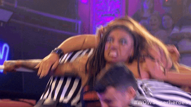 a woman in a striped dress is being lifted by a referee in a wrestling match .