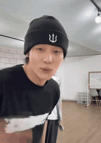 a man wearing a black beanie with a trident embroidered on it
