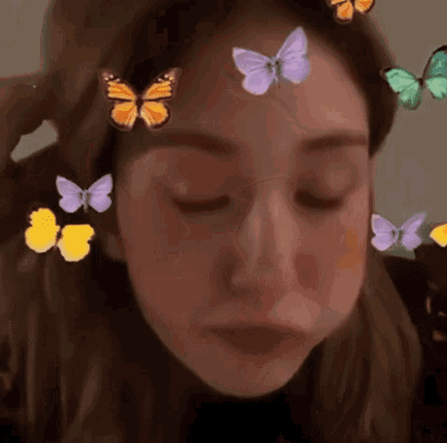a close up of a woman 's face with butterflies on her forehead