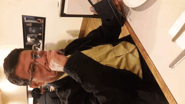 a man wearing glasses is sitting at a table with a menu in his hand