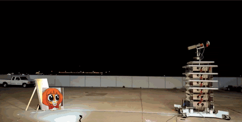 a white truck is parked in front of a tower that is shooting fire