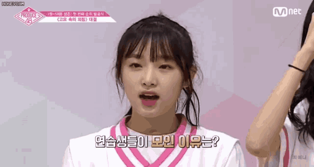 a girl in a pink and white shirt is talking to another girl in a white shirt .