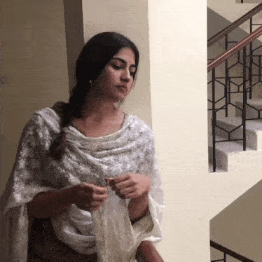 a woman in a white dress is standing next to a railing