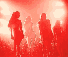 a group of women are standing in front of a red light