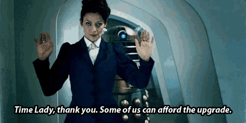 a woman in a suit is standing in front of a robot and says time lady thank you some of us can afford the upgrade