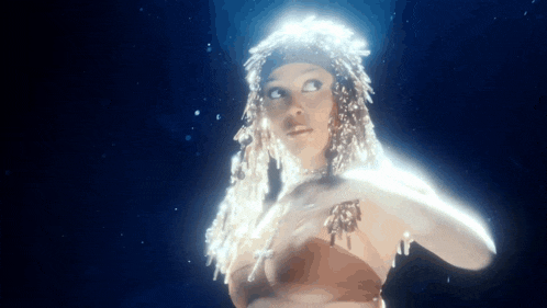 a woman with dreadlocks is standing in the dark with a light shining on her .