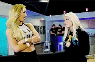 two blonde women are standing next to each other in a room and one of them is wearing a shirt that says " e "