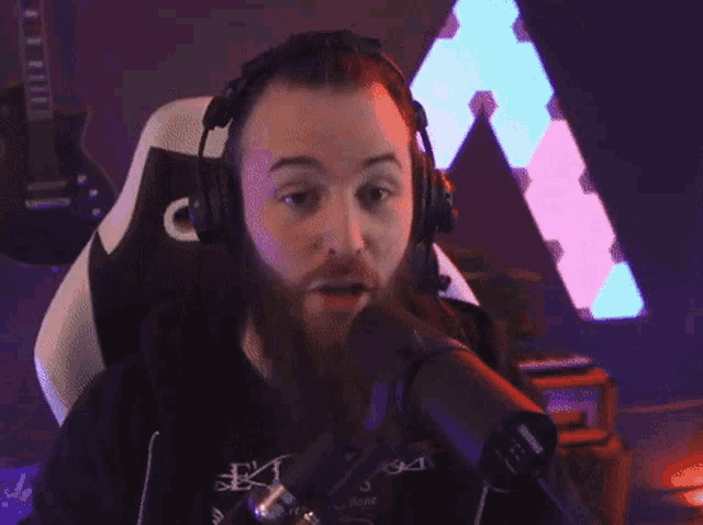 a man with a beard is wearing headphones and giving the peace sign
