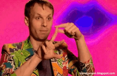 a man in a colorful shirt is making a funny face with his hands .