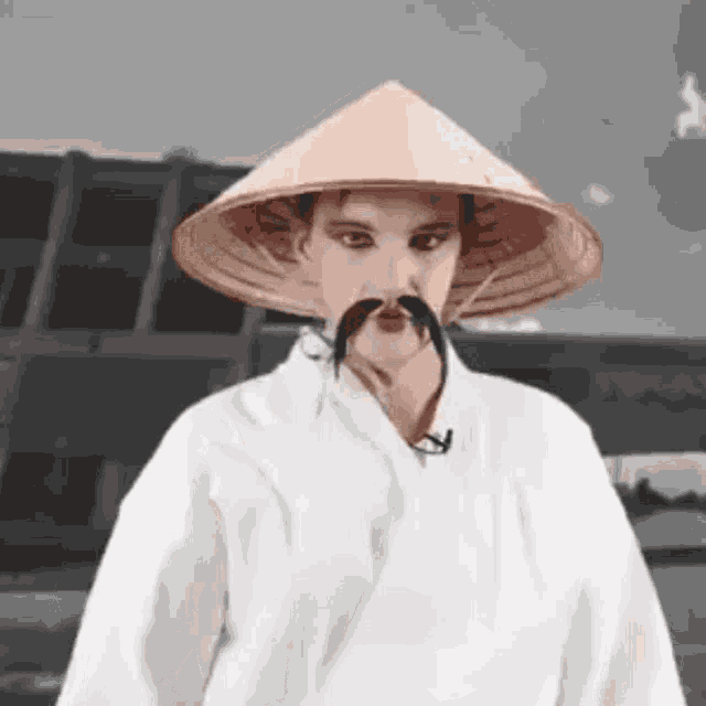 a man with a conical hat and mustache is wearing a white robe