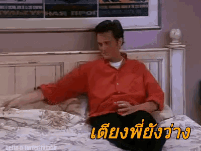 a man in a red shirt is sitting on a bed with a drink in his hand and a foreign language written on the bottom