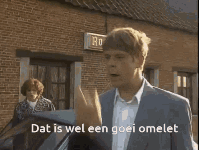 a man in a suit stands in front of a brick building with the words dat is wel een goei omelet written on the screen