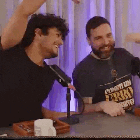 two men are sitting at a table with a microphone .