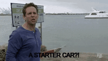 a man in a blue shirt is standing in front of a sign that says " a starter car "
