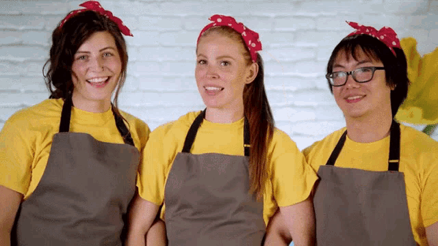 three people wearing aprons and yellow shirts are smiling for the camera