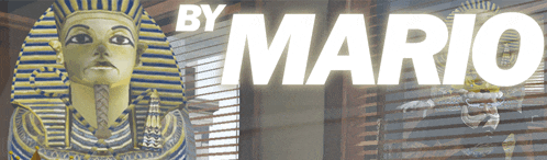 a statue of a pharaoh is behind a sign that says " by mario "