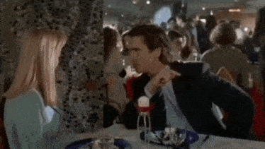 a man in a suit and tie sits at a table with a woman who is covering her mouth