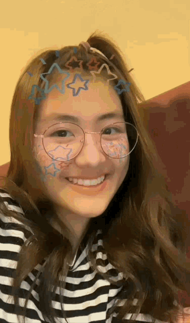 a young woman wearing glasses and a striped shirt smiles for the camera