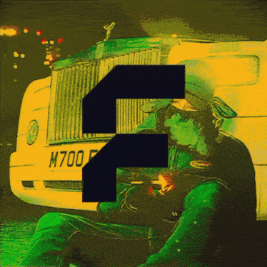 a man is smoking a cigarette in front of a car with a license plate that says m700f