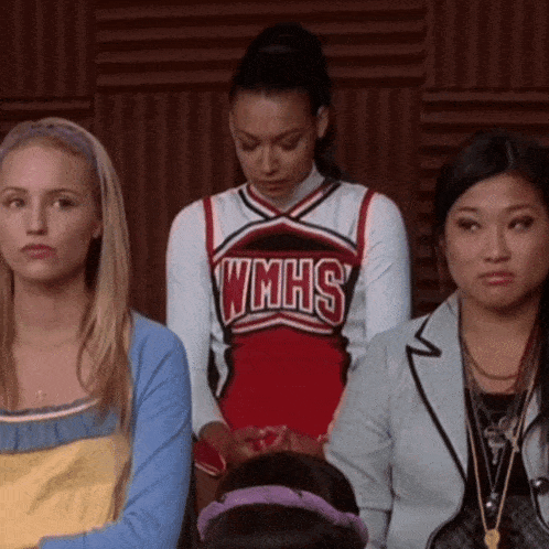 a cheerleader wearing a wmhs uniform stands in front of two other girls