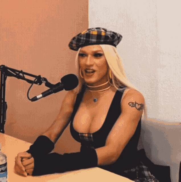 a woman with a tattoo on her arm is sitting in front of a microphone with a bottle of aquafina water in front of her