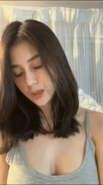 a woman wearing a grey tank top is looking down