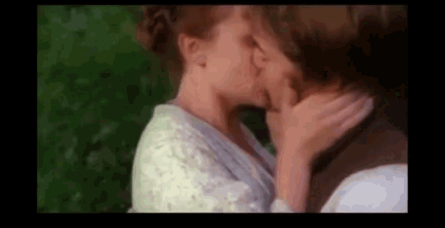 a man and a woman are kissing each other in a park .