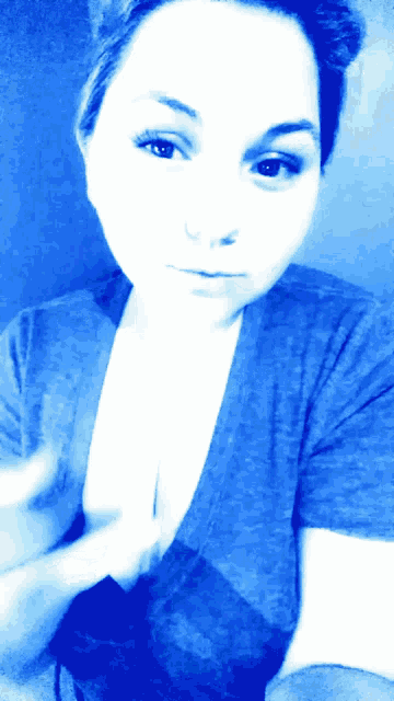 a woman is wearing a blue shirt and taking a selfie