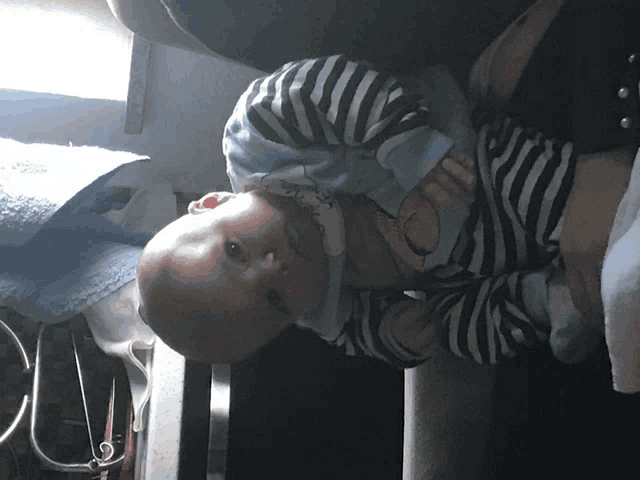 a baby in a striped shirt is laying on its back