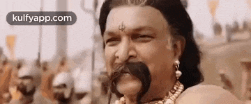 a man with a mustache and a necklace on his neck is smiling .